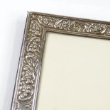 A large modern silver-fronted photo frame, with relief embossed floral and foliate decoration, by