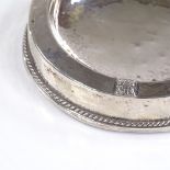 An Arts and Crafts circular silver-mounted pin/ashtray, with planished bowl and gadrooned border, by