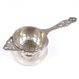 A silver tea strainer and base, with pierced decoration, by Barker Brothers Silver Ltd, hallmarks