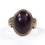 An Antique unmarked gold and cabochon red stone signet ring, with engraved leaf shoulders, setting