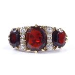 A large 18ct gold garnet and diamond half-hoop ring, with pierced scrollwork bridge, setting