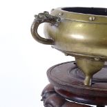 A Chinese bronze 2-handled incense burner, cast dragon decorated handles, raised on 3 feet, with
