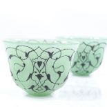 A pair of Islamic green glass tea bowls with painted decoration, diameter 6cm