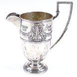 An Edwardian silver helmet-shaped cream jug, with relief embossed Adams style decoration, and gilt