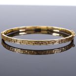 A 9ct gold hinged bangle, with Greek key pattern, band width 3.9mm, internal diameter 60mm, internal