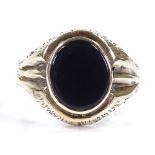 A large unmarked gold onyx signet ring, with brushed bridge and shoulders, setting height 17mm, size