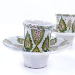 A pair of Turkish pottery coffee cups and saucers, with painted decoration