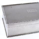 A George V rectangular silver cigarette box, all over engine turned decoration with relief