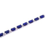 A 14ct white gold sapphire and diamond tennis line bracelet, set with 20 emerald-cut sapphires