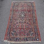 A red ground Middle Eastern wool rug, with central lozenge, 212cm x 125cm