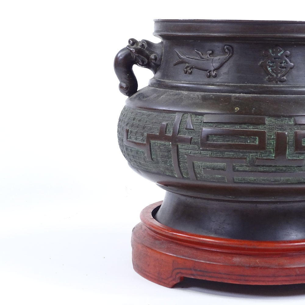 A Chinese bronze incense burner, cast dragon design handles, with relief decorated frieze, rim