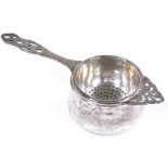 A silver tea strainer and base, with pierced decoration, by Barker Brothers Silver Ltd, hallmarks