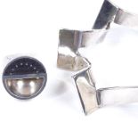 A large unmarked silver stylised ring, size O, together with a silver plated industrial style bangle