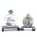 2 Chinese internally painted glass snuff bottles with hardstone tops, on wood stands, largest height