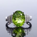 A 14ct white gold solitaire peridot ring, with stepped diamond set shoulders, oval-cut peridot