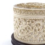 A Chinese 19th century relief carved ivory pot on hardwood stand, 10cm across, height 10cm