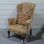 A Queen Anne style upholstered wing armchair on carved walnut legs