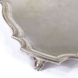 A large George VI square silver tray, with scalloped edge and scrolled foliate feet, by Walker &