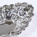 A George V oval silver cake basket, with relief embossed foliate and pierced decoration, by Williams