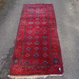 A Persian red and blue ground handmade rug, 9'8" x 4'4"
