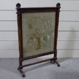 A late Victorian carved mahogany-framed firescreen, with inset needlework panel behind glass, height