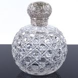 A late Victorian silver-topped cut-glass dressing table scent bottle, with relief embossed floral