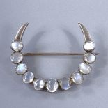 A Victorian unmarked white metal cabochon moonstone crescent moon brooch, largest moonstone length