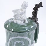 A German porcelain relief moulded beerstein, decorated with figures in a tavern and text, height