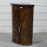 An 18th century figured mahogany bow-front hanging corner cupboard of small size, height 3'