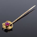 A Victorian unmarked gold ruby stick pin, with engraved foliate folded decoration, pin length 62.
