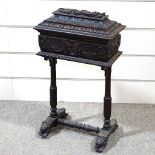 A Victorian carved oak sewing box on stand with high relief carved decoration, on lion mask feet,