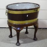 An 18th century brass-bound walnut oval wine cooler, with brass lion-ring handles and cabriole legs,