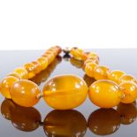 A string of polished graduated butterscotch amber beads, largest bead length 27.7mm, necklace length