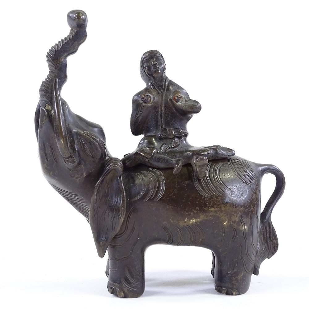 A Chinese patinated bronze incense burner, in the form of a figure seated on an elephant, height