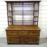 An Antique oak dresser with open plate rack, 3 frieze drawers and panelled cupboards under, length