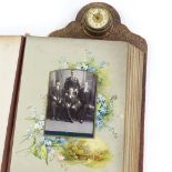 A Victorian leather-bound photograph album, with brass-mounted clock set to the pediment, the