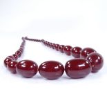 A string of graduated cherry amber beads, largest bead length 30.4mm, necklace length 86cm, 108.6g