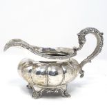 A George III silver cream jug, of lobed melon form with cast scrolled handle, by Rebecca Emes and