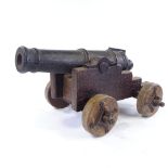 A cast-iron ornamental cannon on wooden-wheeled carriage base, probably early to mid-20th century,