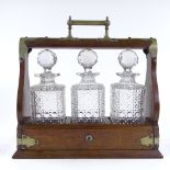 A Victorian oak tantalus with electroplate mounts, containing 3 original square cut-glass decanters,