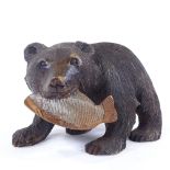 A Black Forest carved wood grizzly bear holding a fish, length 30cm
