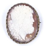 A relief carved cameo shell panel brooch, depicting portrait of Zeus, in unmarked yellow metal