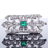 An Art Deco unmarked white metal emerald and diamond cluster panel brooch, with scrollwork settings,