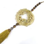 A Chinese carved and pierced nephrite jade disc, with tiger's eye bead suspension and silk tassel...