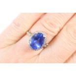 Tanzanite and diamond cluster ring, the central oval cut tanzanite of approx. 3cts, bordered with