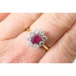 Ruby and diamond cluster ring, the oval cut ruby of approx. 0.5ct, in a four claw stepped mount