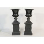 Pair of cast iron campagna pedestal urns, each standing on a square plinth cast with a laurel leaf