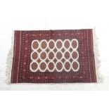 Pakistani woollen rug, Bokhara style, fawn field with three rows of botehs within a madder border,