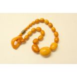 Butterscotch amber graduated bead necklace, set with oval beads graduating in size, the largest