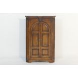 Oak flat front hanging corner cupboard, early 19th Century, having a moulded cornice over two